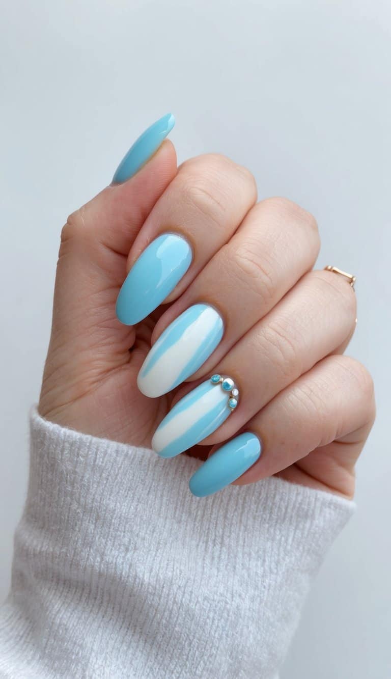 A soft blue nail design with white swirls and delicate rhinestone accents, creating an elegant and stylish manicure.