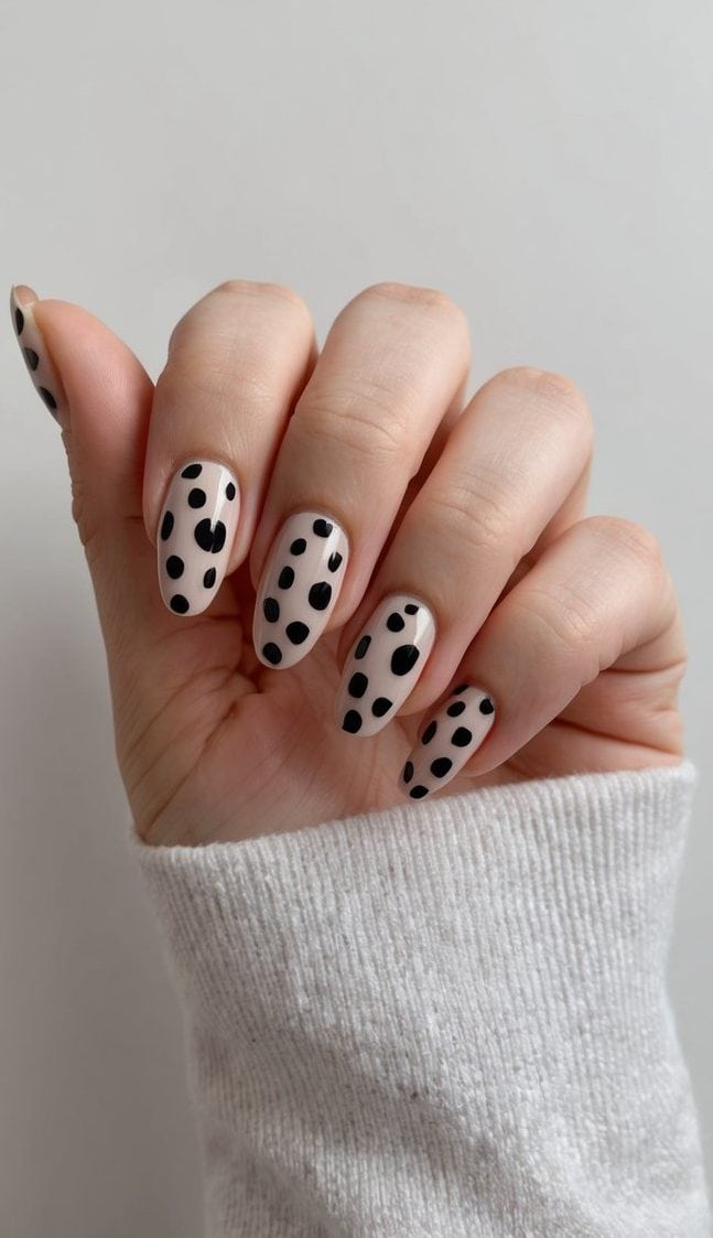 A close-up of ladybug-inspired nails on a clean, neutral background