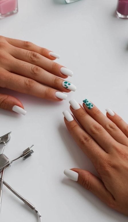 A table with various nail polish bottles, nail art tools, and a pair of hands demonstrating a simple nail art design