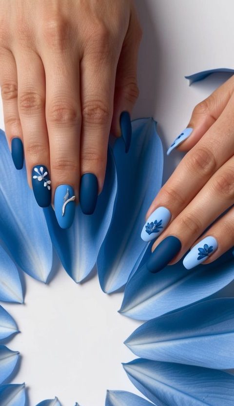 A close-up of soft blue petals arranged in a circular pattern, with 50 different blue matte nail art designs displayed on each petal