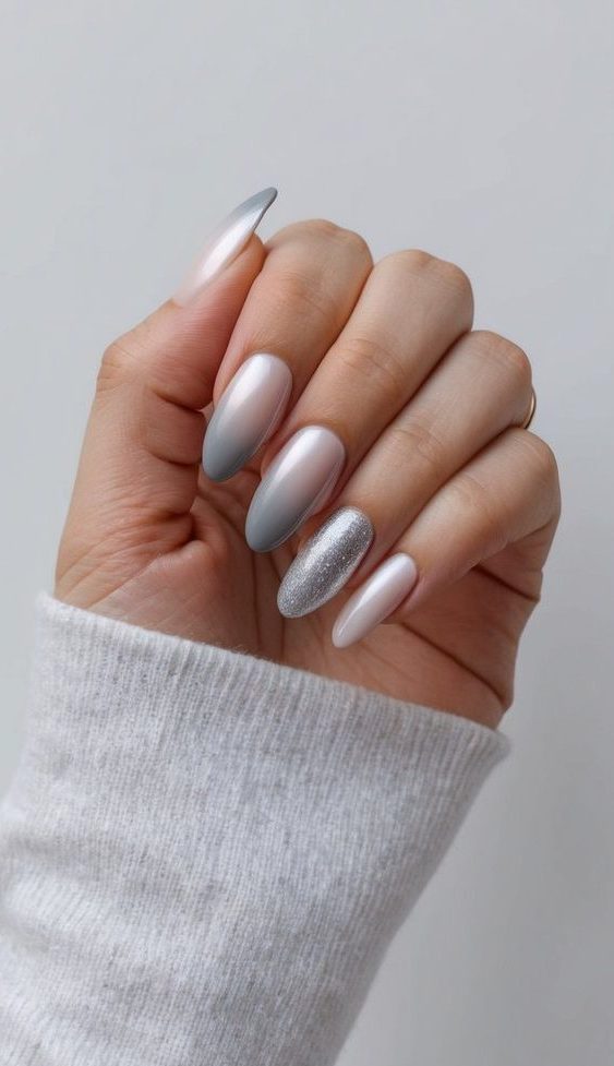 A hand holding a polished pearl overlay nail with a gradient gray ombre design on a clean, minimalist background