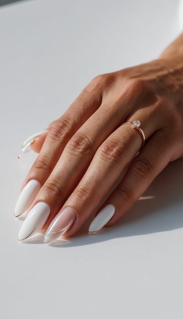 A hand resting on a smooth, white surface adorned with a clear crescent tip minimalist nail art design