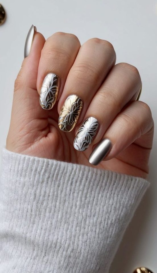 A hand holding a nail with intricate metallic floral patterns, surrounded by various metallic accent nail art designs