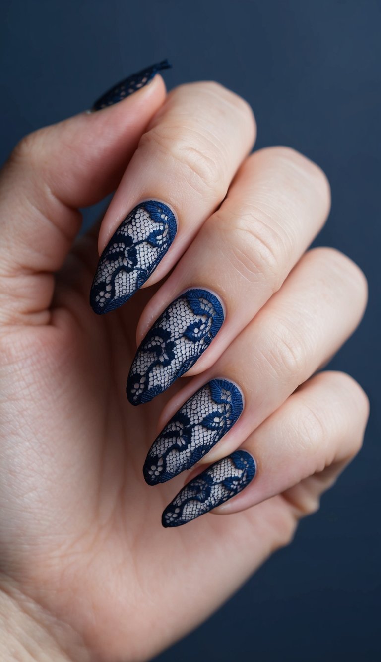 A navy lace nail art design on a clean, manicured nail against a dark, solid background