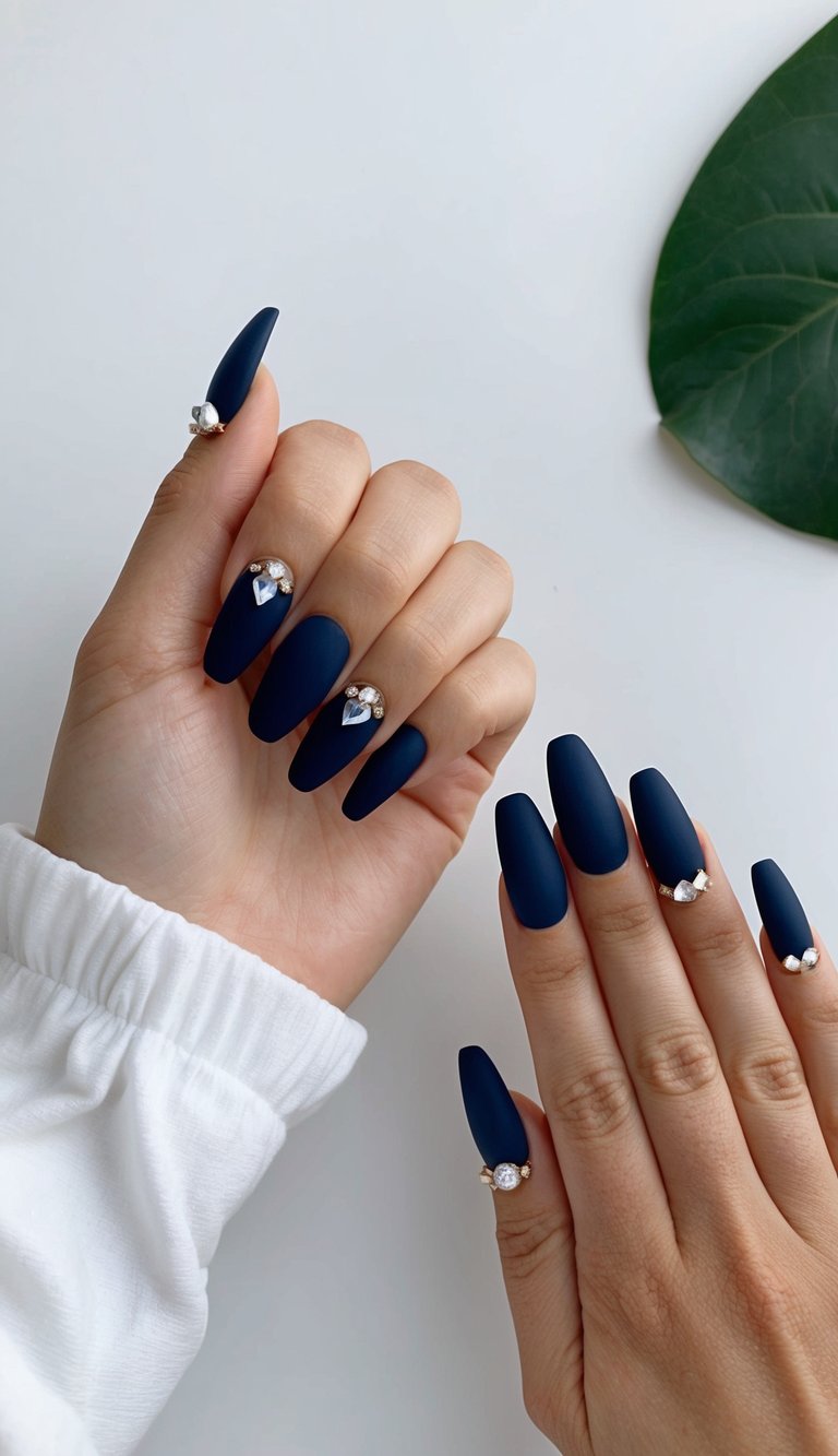Navy matte nails with crystal accents displayed on a clean, minimalistic surface