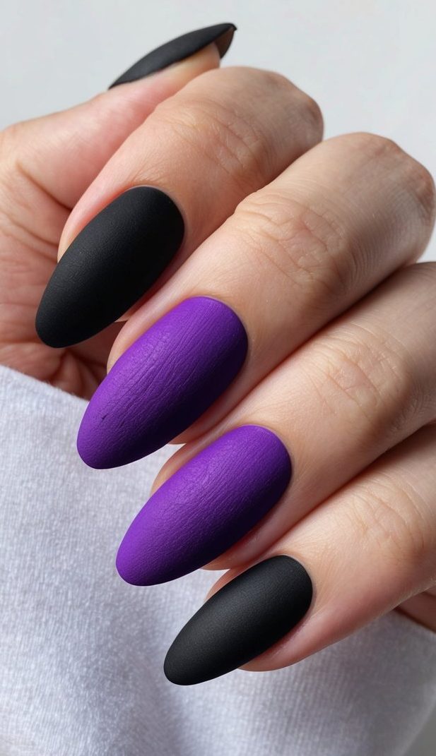 A close-up of purple and black nails with a textured matte finish