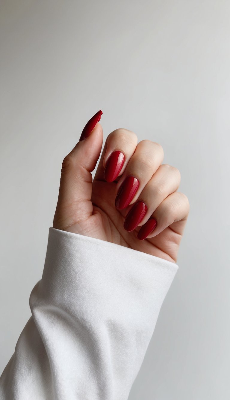 A hand with classic red French manicure against a white background