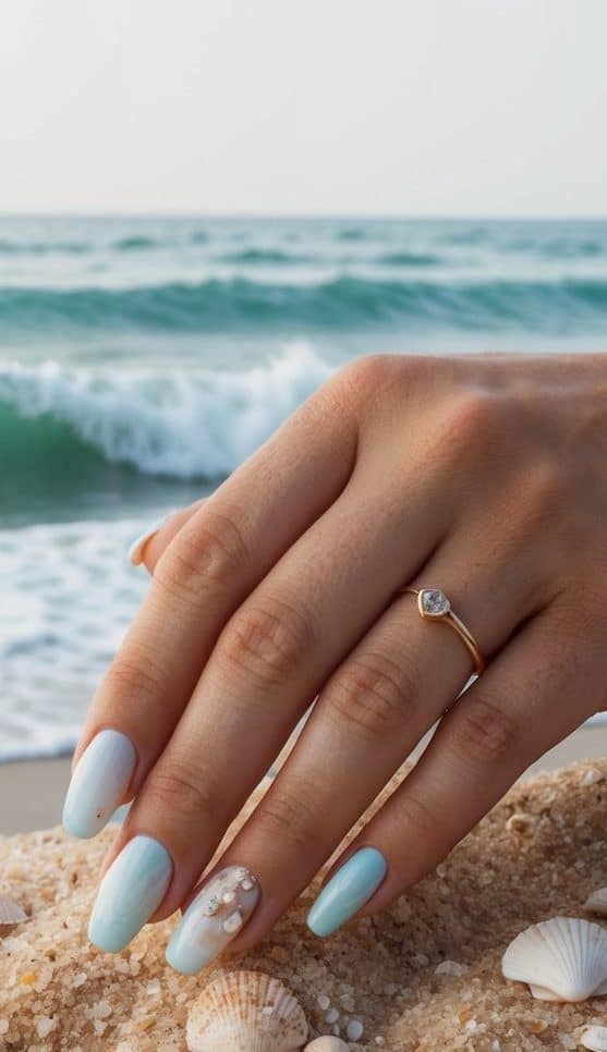 Soft pastel waves crashing onto sandy beach, with seashells scattered among them