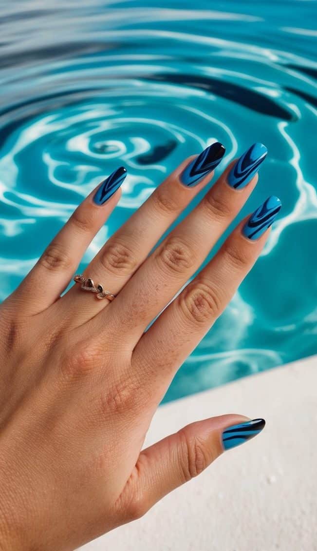 A serene blue lagoon with swirling black and blue nail art designs floating on the water's surface