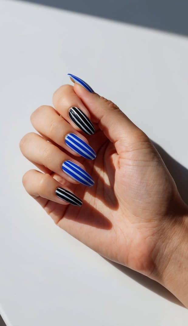 A close-up view of black and blue striped nail art on a sleek, modern background