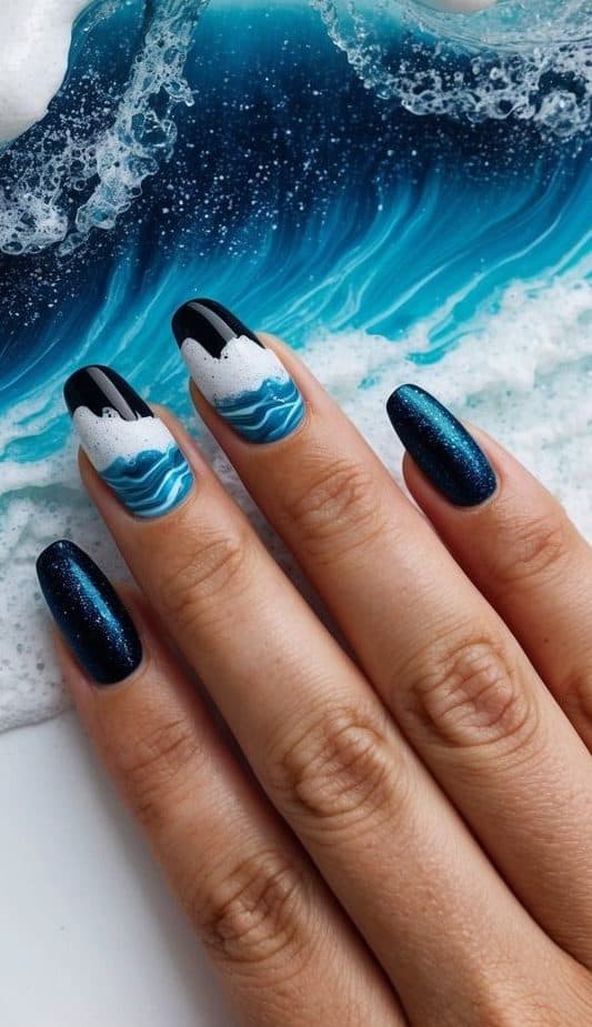 The scene features sparkling seafoam waves crashing against a black and blue nail art design