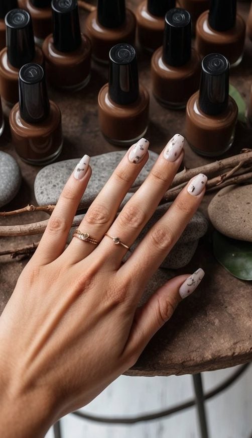 A rustic table with 50 brown nail polish bottles, surrounded by earthy elements like twigs, leaves, and stones