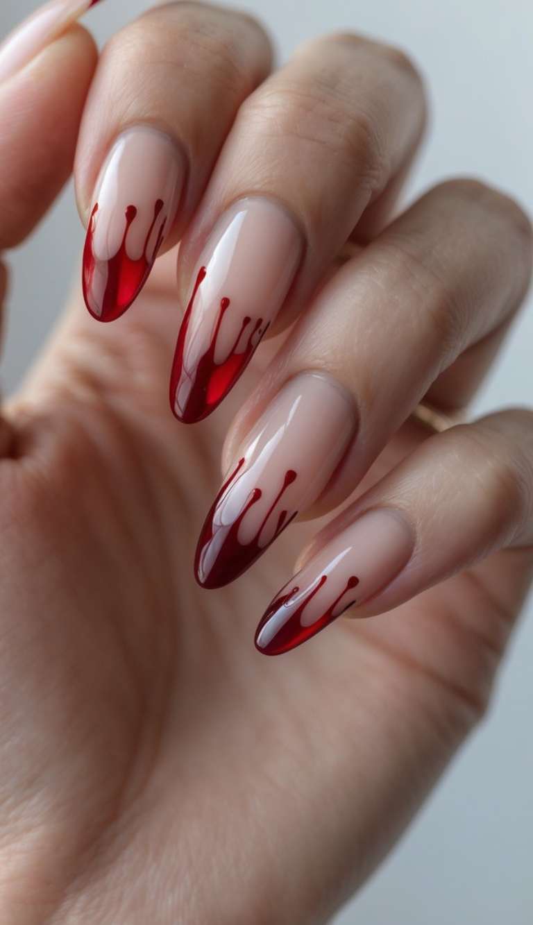 Blood red tips with a drip effect on a soft nude base make for a daring, dramatic Halloween mani