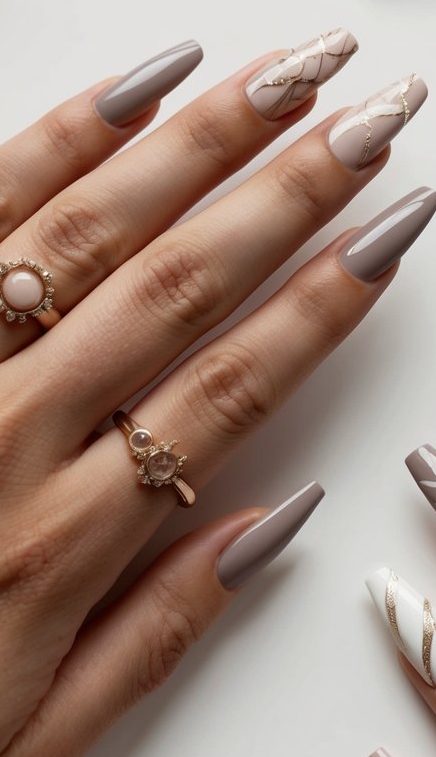 Glossy taupe nails with blush quilted accents and thin gold lines, blending elegance with fine detailing.