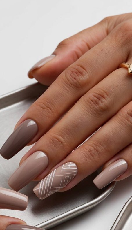 Almond-shaped taupe nails in varied neutral shades with a white crisscross line design for a soft yet sophisticated finish.