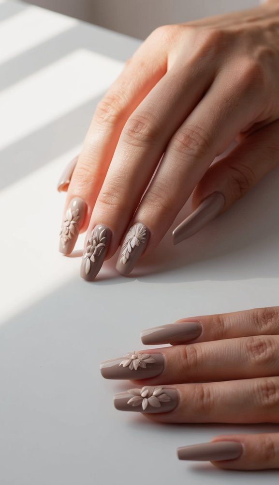 Taupe nails with raised 3D floral accents on a glossy finish, combining texture and femininity in a soft, neutral palette.