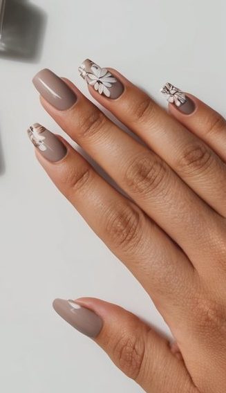 Glossy taupe nails featuring small white daisy flowers and fine accents for a light, feminine floral manicure.