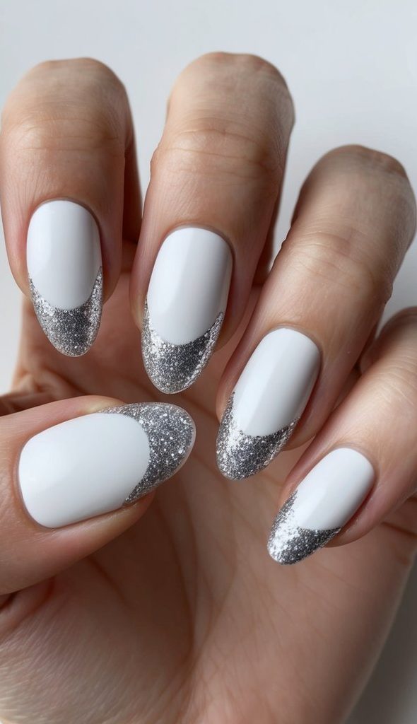 Glossy white nails topped with silver glitter crescent tips, combining soft shine and festive sparkle in a chic nail design.