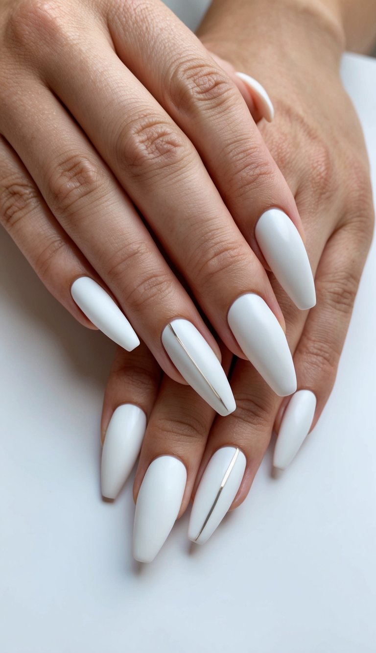 Polished almond-shaped white nails accented by thin gold stripes on two fingers, showcasing a clean and luxurious minimalist look.