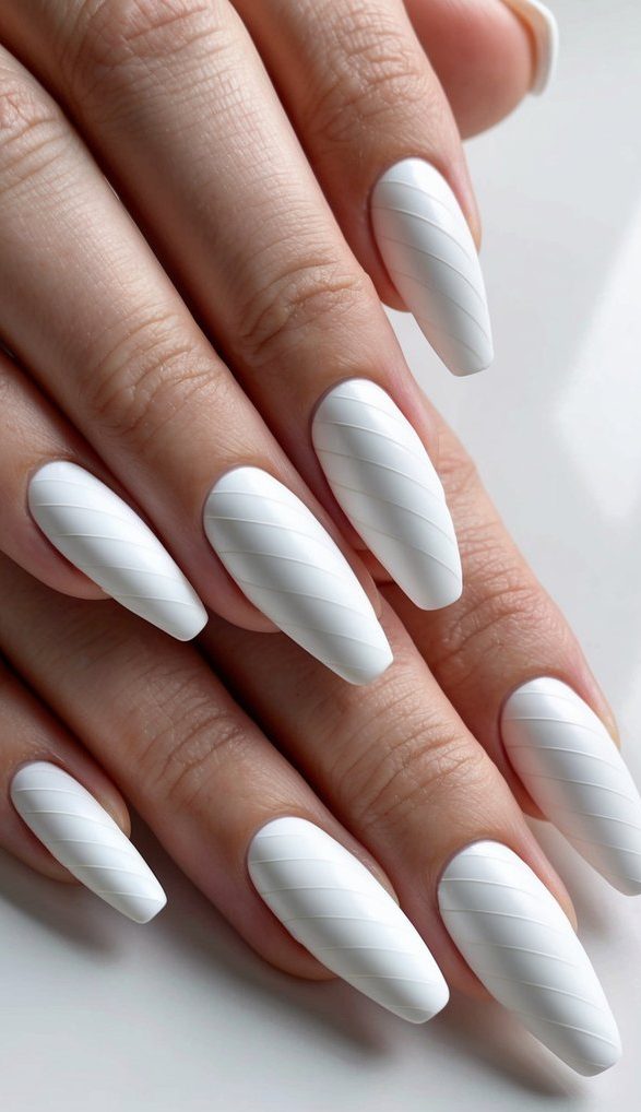 Crisp matte white nails with sculpted diagonal swirl patterns adding elegant texture.