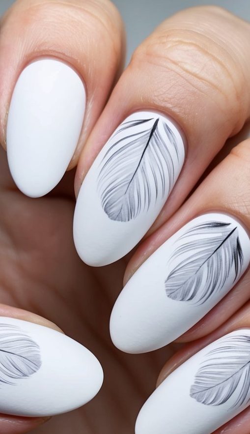 Close-up of matte white nails with detailed gray feather illustrations for a soft, airy design.