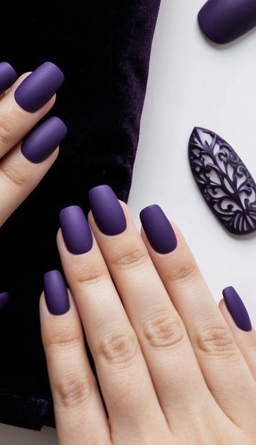 Hands with matte dark purple nails in a bold square shape, highlighting a luxe and modern style.