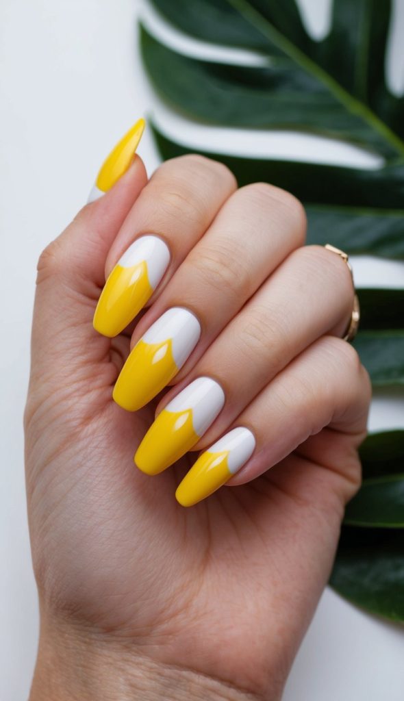 Vivid yellow French tips shaped into peaks over white polish, creating a striking contrast with a tropical flair.