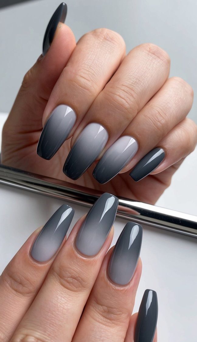 Nails featuring a bold gray ombré, fading from light smoky bases to sharp charcoal ends with a shiny, trendy finish.