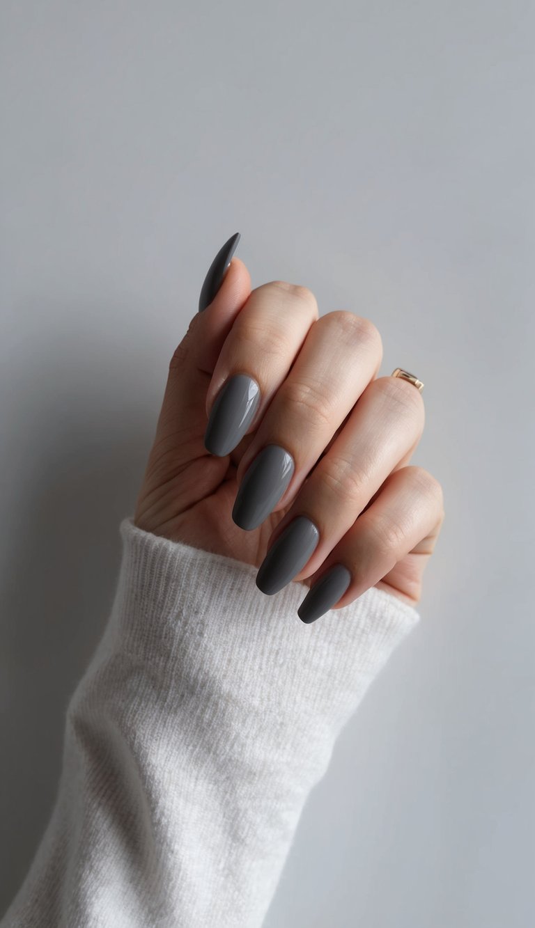 Hand with shiny dark gray nails against a white sweater, creating a cozy and effortlessly stylish manicure look.