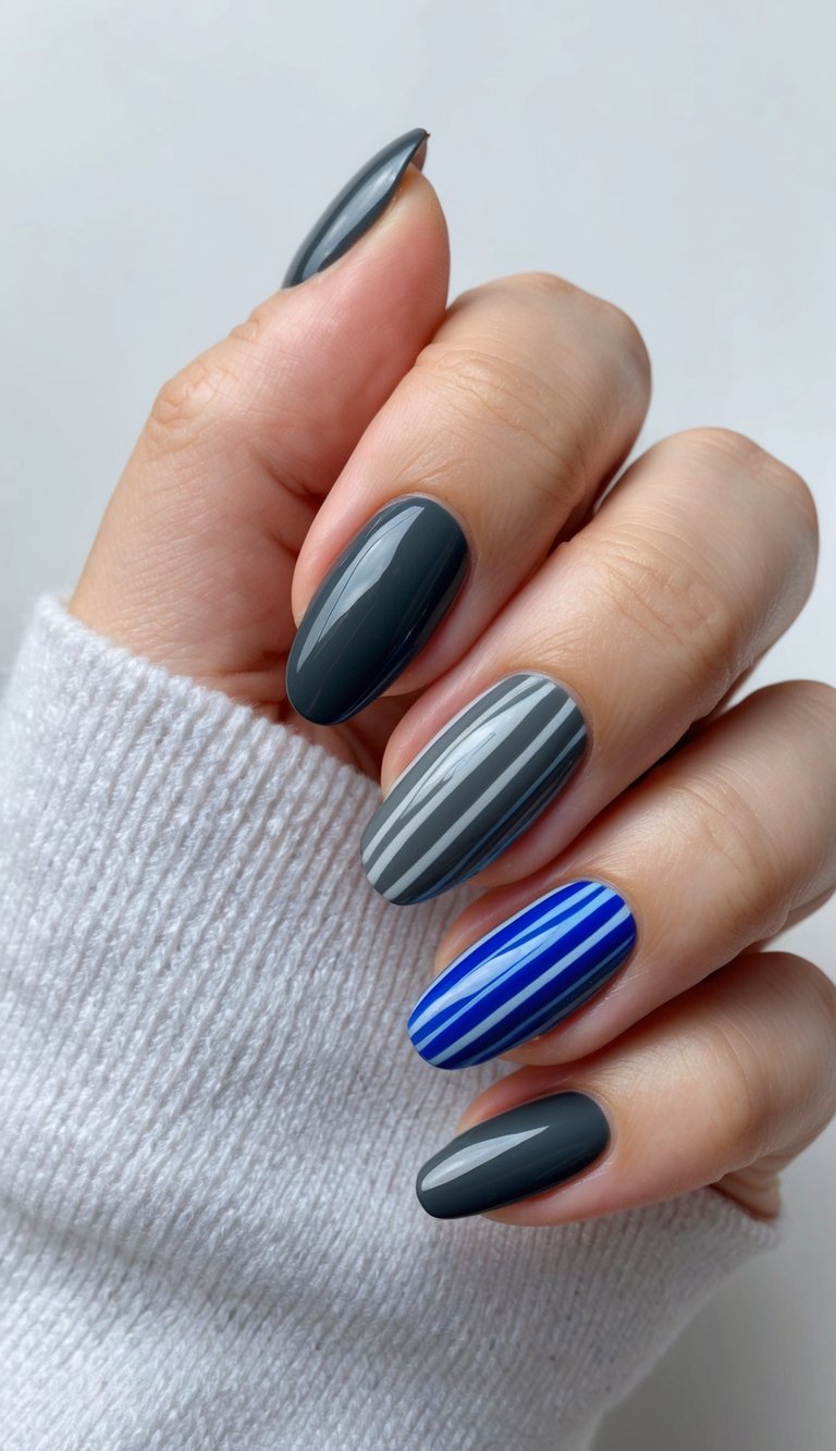 Glossy charcoal nails paired with striped gray and cobalt blue accents for a bold and trendy look.