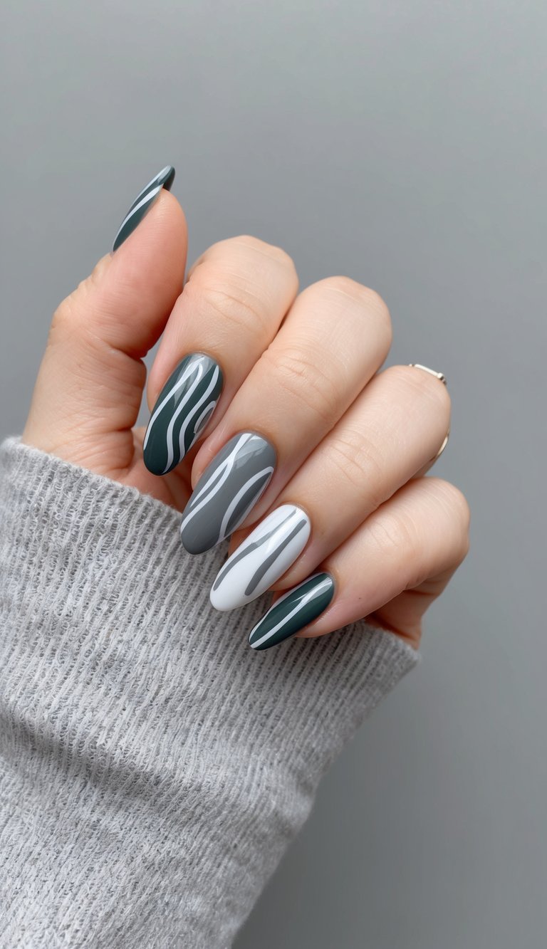 Gray and white swirl nail art on charcoal and white bases, blending minimal tones with a sleek flowing design.