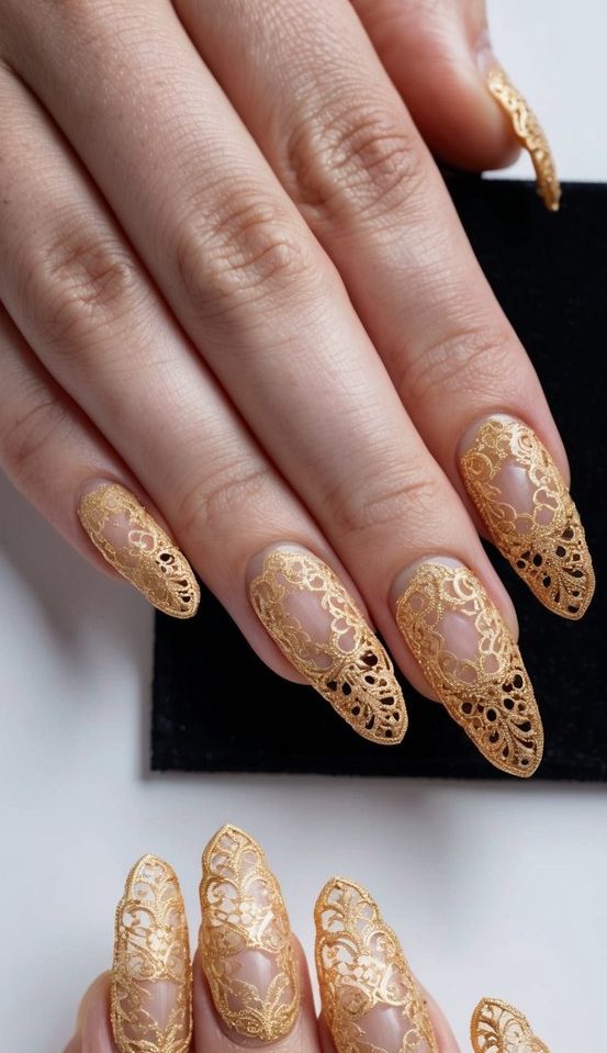 A close-up of intricate gold filigree lace nail art on a black background