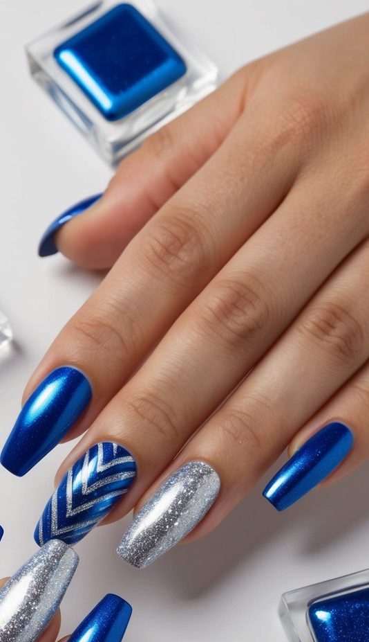 Royal blue and glittery silver nails with one chevron-accented nail, creating a bold, glam-inspired blue and silver nail art look.