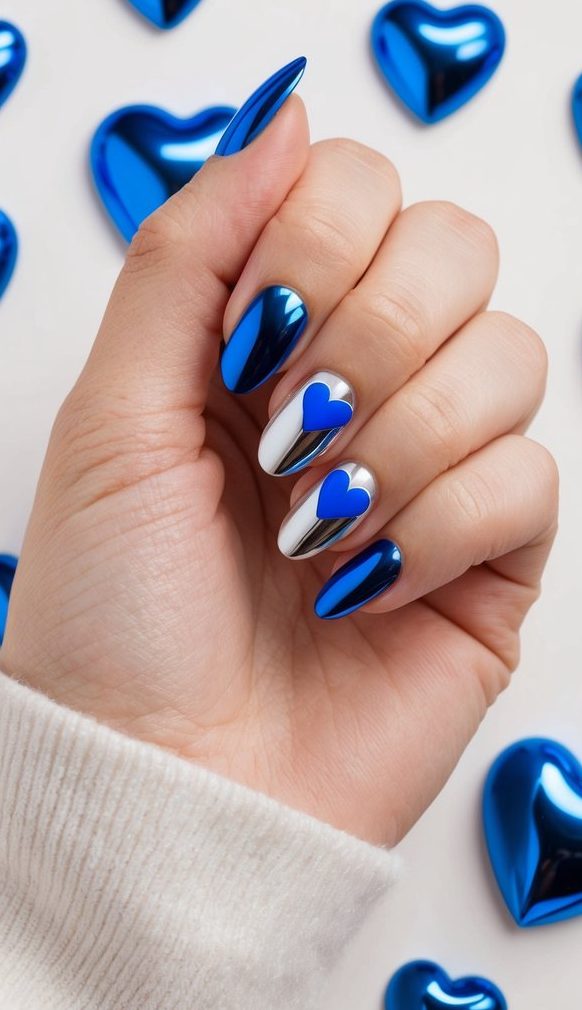 A hand holding a nail with blue chrome heart accents, surrounded by various blue chrome nail art designs