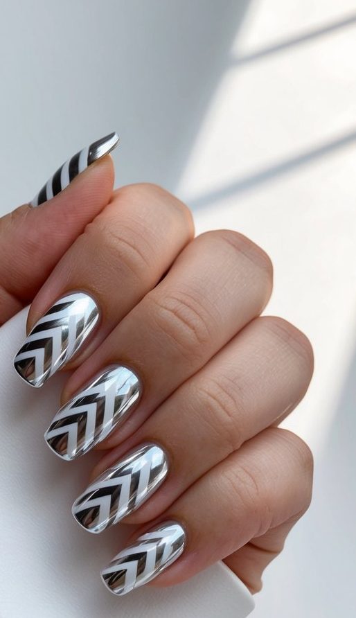 A close-up of zigzag white chrome nail art on a sleek, modern surface