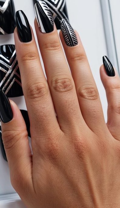 Hand with black nails and accent nails displaying silver linear tribal patterns for a structured and modern nail art look.