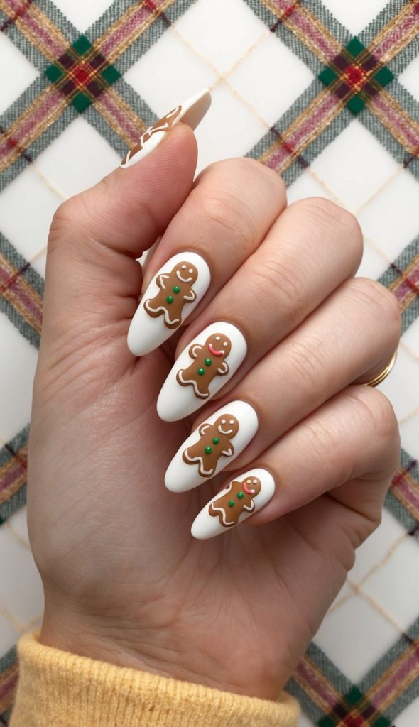 Clean white holiday nails with gingerbread characters outlined in icing and finished with green candy accents.