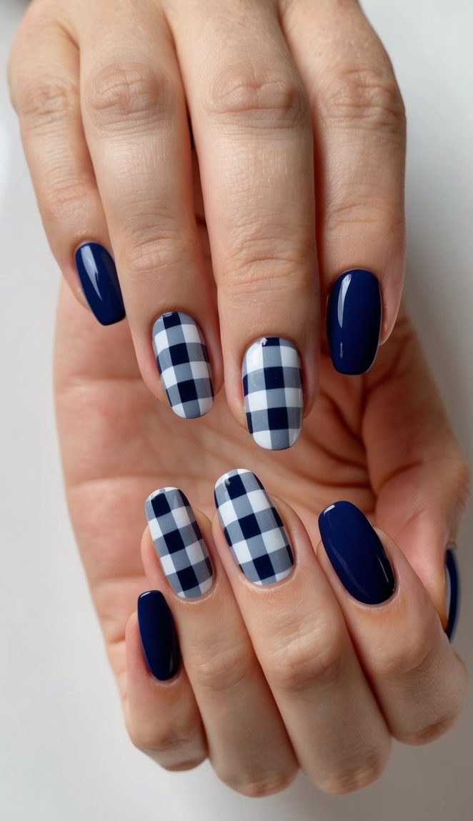 A close-up of navy blue nails with gingham charm design on a clean, white background