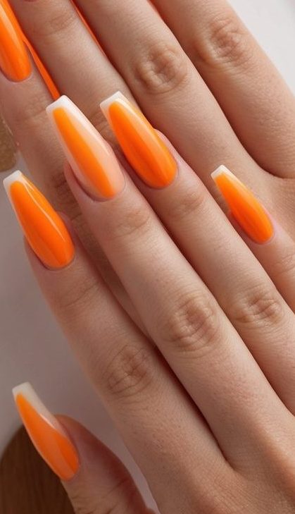 Vibrant orange nails with sharp milky tips and negative space detailing, showcasing a bold and glossy nail art idea.