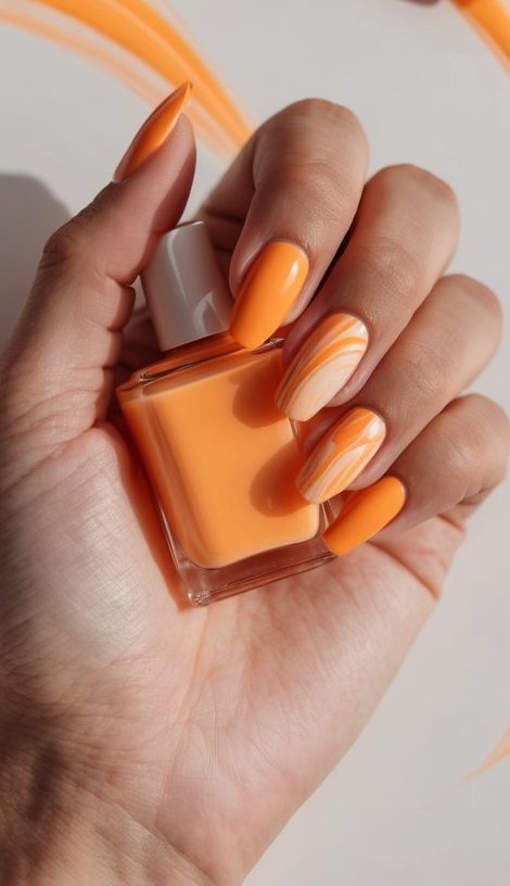 Glossy tangerine nails with two marbled swirl accents in creamy orange and white tones, perfect for fresh orange nail inspiration.