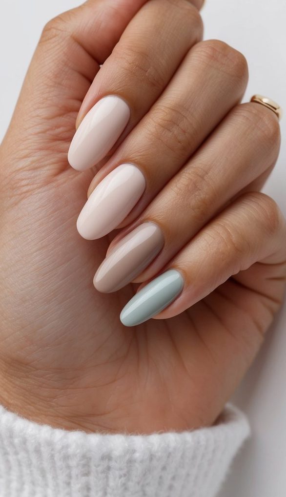 A hand holding a soft pastel ombre nail polish palette, with neutral shades blending from light to dark