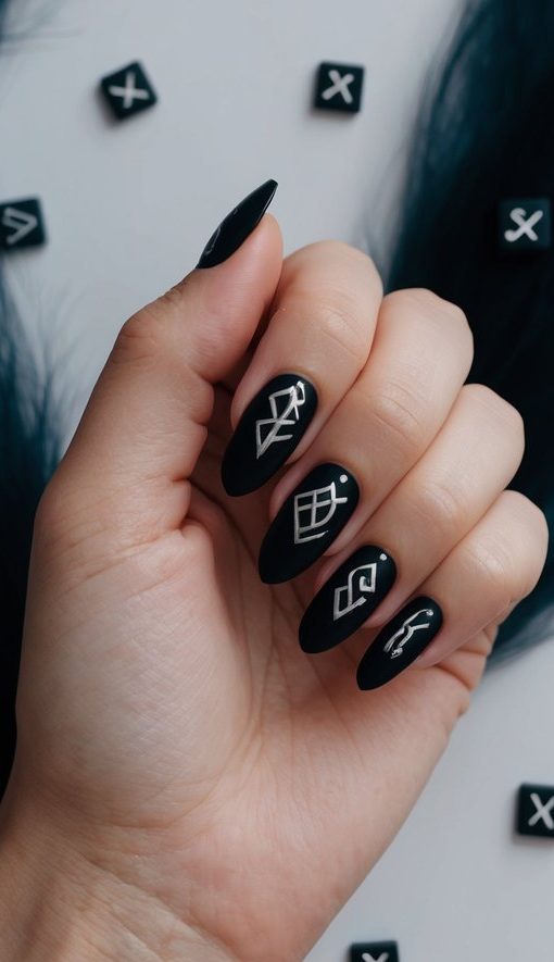 Matte black nails with white abstract rune-like symbols for a sleek, modern emo nail design.