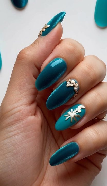 Ocean-inspired teal nails with gold flower foil and crystal accents, styled for a glam January look.