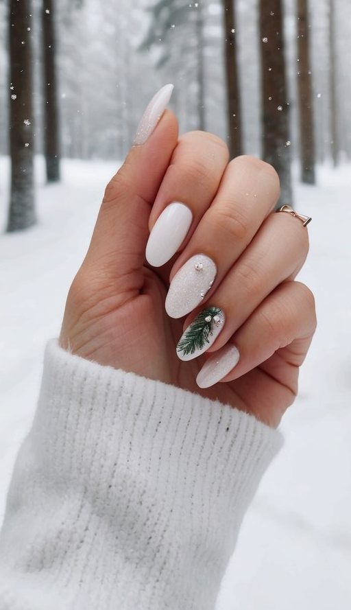 Frosted white nails with an evergreen sprig and crystals, perfect for an elegant January nail look.