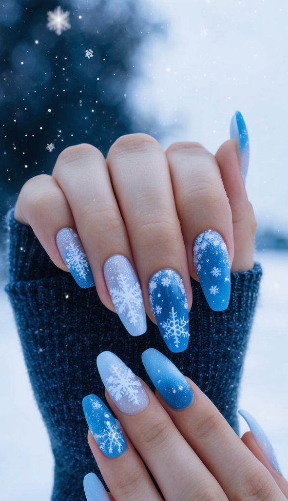 Gradient blue and white nails with delicate snowflake designs, resembling a snowy winter night.