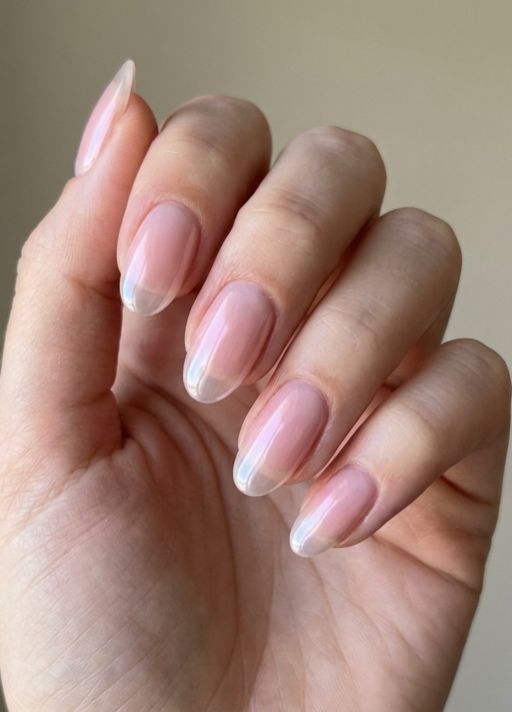 Hand close-up revealing a light, airy glazed nail art idea with pale pink gloss and naturally transparent tips.