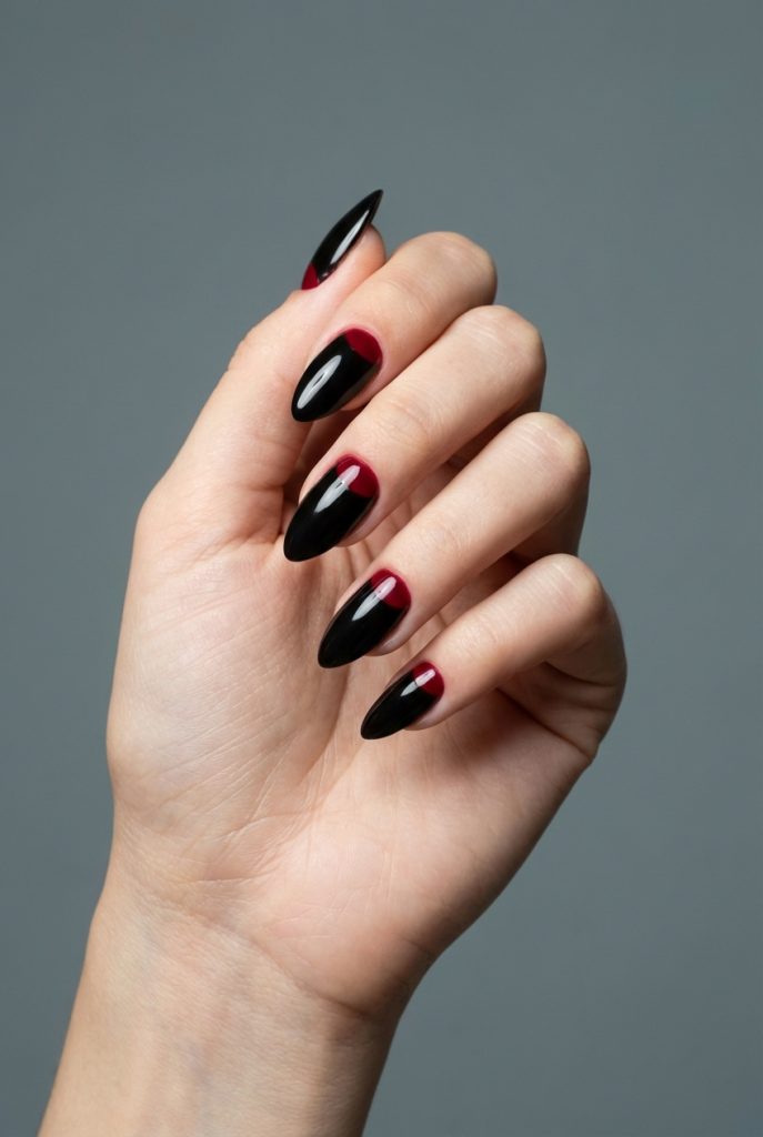 Almond-shaped nails styled in reverse French nail art idea, combining rich black polish with glossy maroon half-moon shapes at the base of each nail.