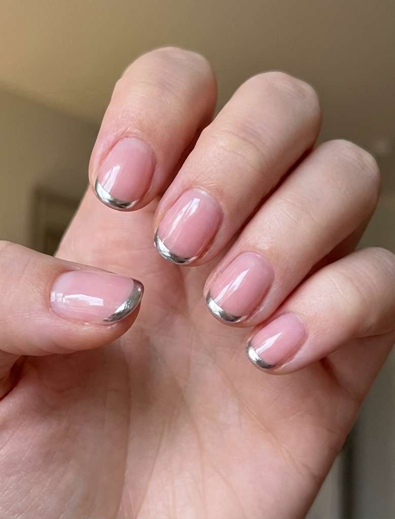 Close-up of a hand featuring glossy nude-pink short nails with precise silver chrome tips, creating a refined and elegant short nail art idea.