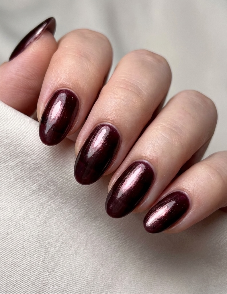 Almond nails with a glazed nail art idea in deep crimson chrome, reflecting berry and cherry tones with a high-gloss finish.