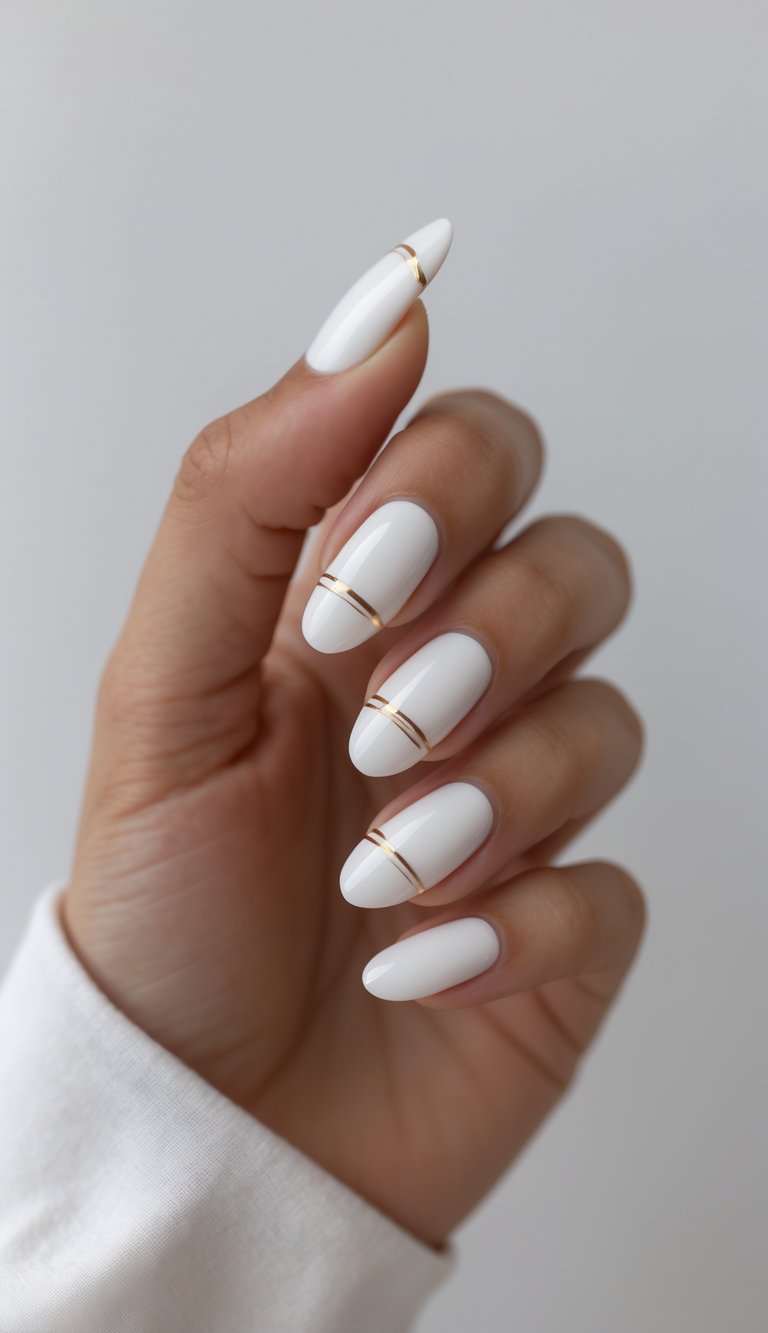 Close-up of hand with white glossy nails decorated with gold metallic bands, a luxe-inspired glossy nail art idea for a clean yet glamorous vibe.